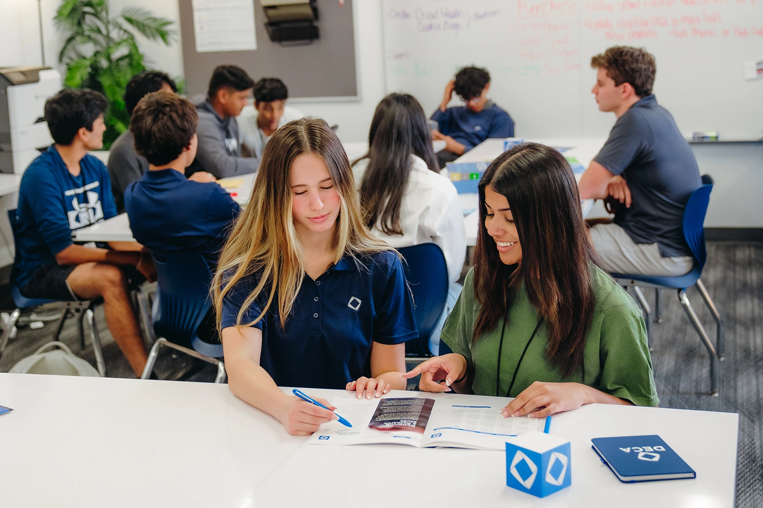 DECA students looking at a magazine smiling